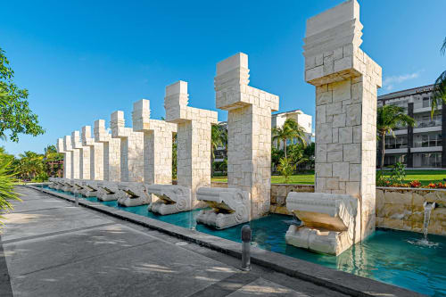 Fuente acuática con columnas de piedra del Resort Mareazul frente al mar, con canal turquesa en Playa del Carmen