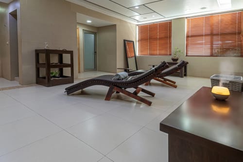 Área moderna de relajación spa en Mareazul Resort Beachfront con tumbonas, estanterías de madera e iluminación cálida en Playa del