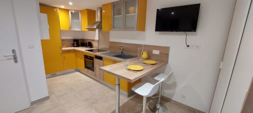 Cuisine jaune moderne avec espace repas à la Gîte Pâquerette du Mas de Trépeloup, Alès, avec TV murale