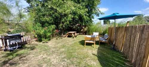 Terrasse de jardin ombragée au Mas de Trépeloup avec mobilier en bois, parasol et pelouse près d'Alès, France