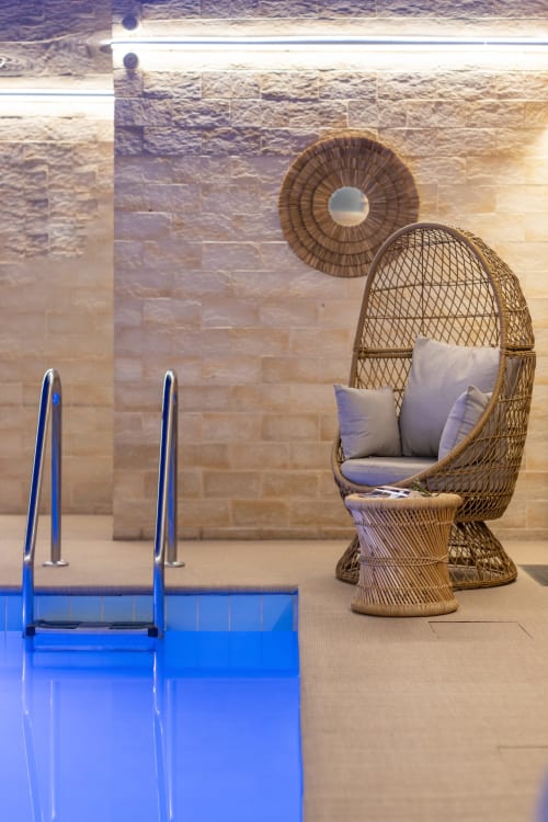 Espace piscine luxueux de l'Hotel Residence Europe & Spa avec fauteuil oeuf en rotin et bassin bleu à Clichy