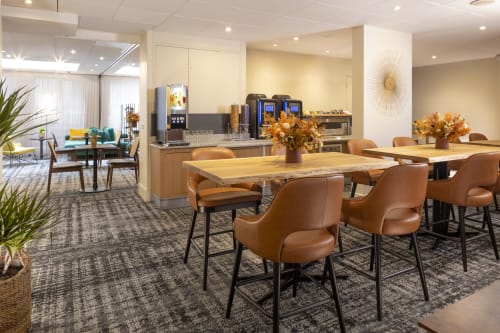 Modern hotel lounge at Hotel Residence Europe & Spa with leather bar stools, wooden tables, and golden floral decor