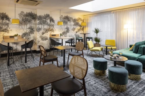 Modern lounge area at Hotel Residence Europe & Spa in Clichy with yellow pendant lights, green seating, and nature-inspired