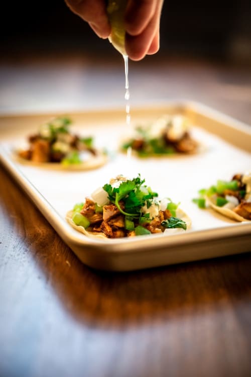 Chef rociando jugo de lima sobre tacos gourmet en Mareazul Resort Frente al Mar en Playa del Carmen, con cilantro y ingredientes frescos