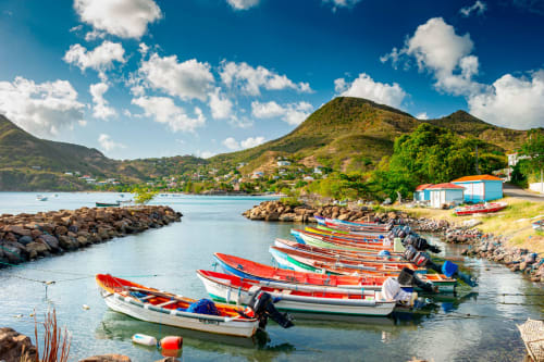 Bateaux de pêche colorés dans les eaux turquoise des Anses d'Arlet, Martinique, avec des montagnes verdoyantes