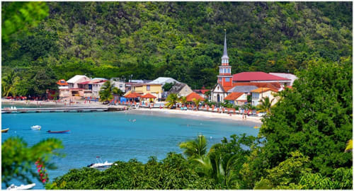 Village côtier coloré avec clocher, baie turquoise, bateaux et collines verdoyantes aux Anses d'Arlet, Martinique