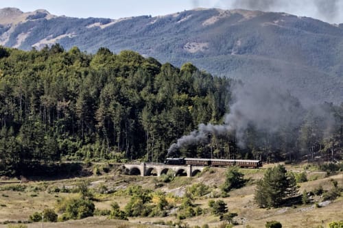 Histórico tren de vapor cruzando un puente de piedra en las montañas de Abruzzo cerca de Sulmona, Italia