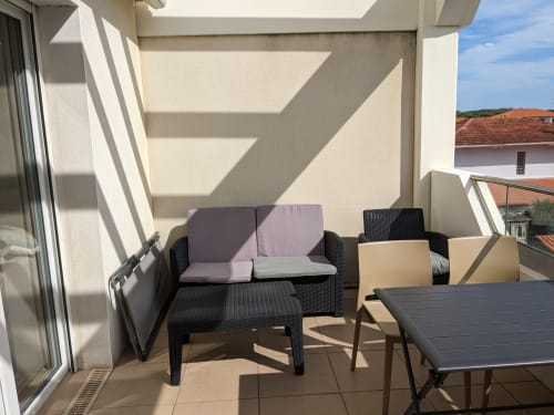 Coin séjour ensoleillé à Côte Et Dune avec mobilier en rotin et vue mer sur Biscarrosse Plage