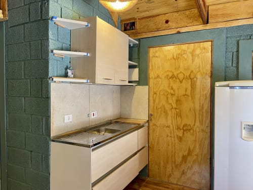 Kitchenette compacta no Paraíso nas Montanhas com fogão, armários de armazenamento e porta de madeira em Campos do Jordão