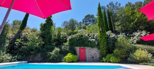 Des parasols rose vif ombragent une piscine étincelante au Mas de Trépeloup, un gîte rural français près d'Alès