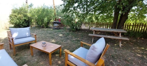 Zone de détente extérieure au Mas de Trépeloup avec mobilier en bois et coussins bleus à Alès