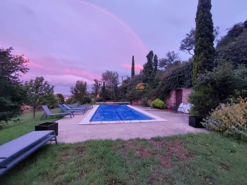 Vue crépusculaire de la piscine rectangulaire du Mas de Trépeloup avec transats, cyprès et jardins entretenus à Alès, France