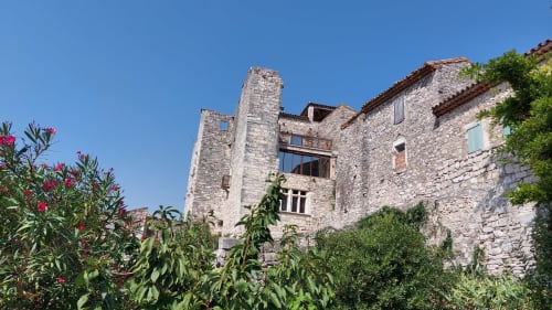 Tour médiévale en pierre et bâtiments du Mas de Trépeloup à Alès, France, entourés de plantes fleuries