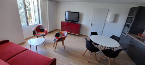 Salon moderne du gîte Le Mas de Trépeloup à Alès avec fauteuils rouges, table à manger, télévision et kitchenette