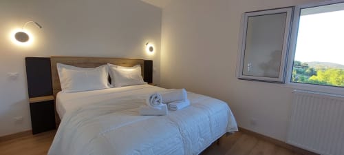 Chambre moderne du Mas de Trépeloup avec literie blanche, appliques murales et vue sur la campagne