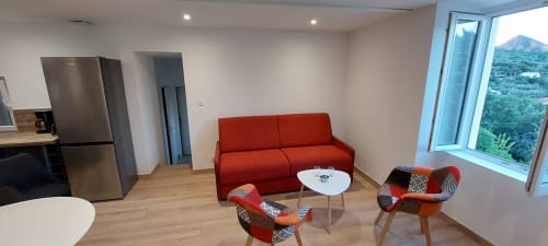 Lounge moderne du Mas de Trépeloup avec canapé rouge, fauteuils et vue sur les montagnes à Alès