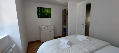 Chambre lumineuse au gîte Le Mas de Trépeloup à Alès avec lit blanc, commode en bois et décoration verte