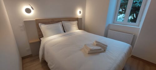 Chambre moderne et épurée au Mas de Trépeloup B&B à Alès, France avec literie blanche et tête de lit en bois