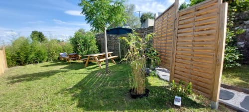 Terrasse ensoleillée du gîte Le Mas de Trépeloup à Alès avec clôture en bois, table de pique-nique et plantes