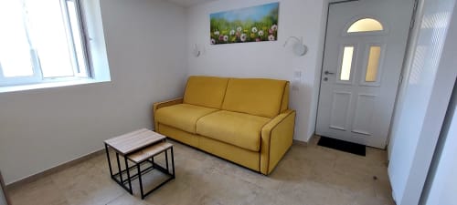 Canapé jaune éclatant avec tables gigognes dans la chambre d'hôte du Mas de Trépeloup, Alès, France