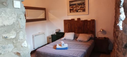 Acogedora habitación en el albergue La Calma De Bellver en Bellver de la Cerdanya con cabecero de madera y paredes de piedra