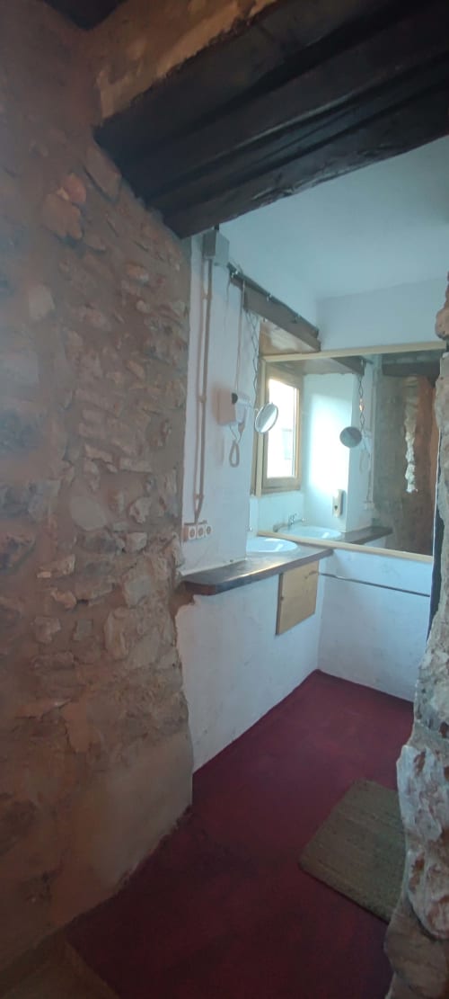 Baño del hostal La Calma De Bellver en Bellver de la Cerdanya con lavamanos, espejo, ducha y piso rojo