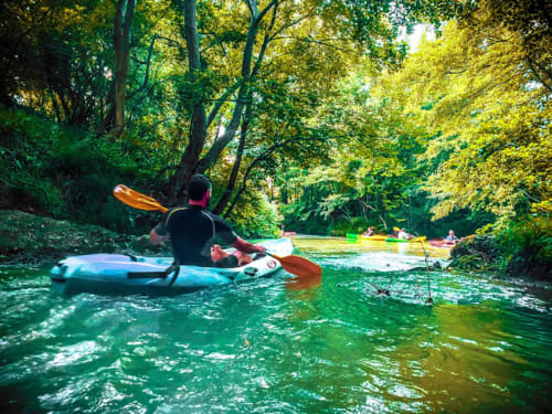 Kayaker paddling on emerald river surrounded by lush trees at Les Gites de Campardon, Monties