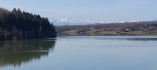 Serene lake view with snow-capped Alps, forests, and countryside near Les Gites de Campardon, Monties