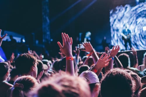 Folla di spettatori a Myob Roma con mani alzate e luci di scena durante l'evento live