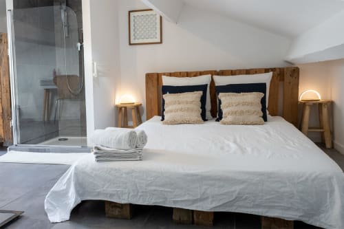 Spacieuse chambre au Mas Lafleur avec lit en bois, draps blancs, salle de bain privée et équipements modernes à Châteaurenard