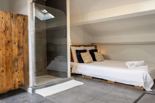 Modern attic bedroom at Mas Lafleur in Châteaurenard with wooden bed, glass shower, skylight, and neutral décor