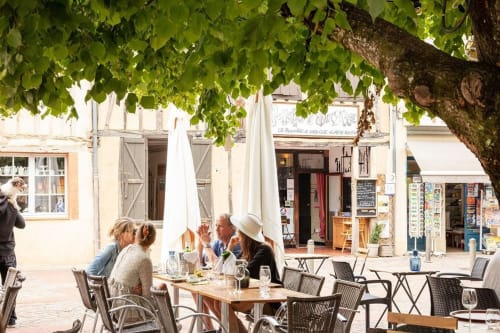 Outdoor terrace dining at Les Gites de Campardon in Monties, France, with guests seated under leafy shade