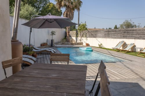 Terrasse piscine du Mas Lafleur avec transats, parasol noir et eau cristalline à Châteaurenard