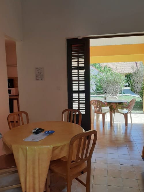 Salle à manger avec nappe jaune et chaises en bois ouvrant sur la vue du jardin de l'hôtel Mon Refuge, Martinique