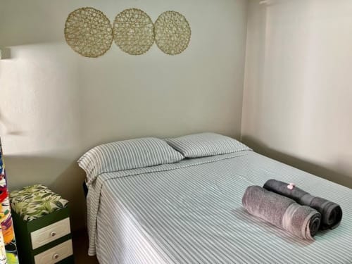 Quarto limpo e aconchegante no Hostel New Ipanema com cama de listras, toalhas enroladas e arte decorativa na parede do Rio de Janeiro