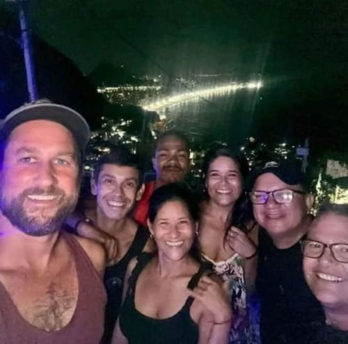 Grupo de hóspedes sorrindo na Pousada New Ipanema no Rio de Janeiro com vista da baía e luzes da cidade