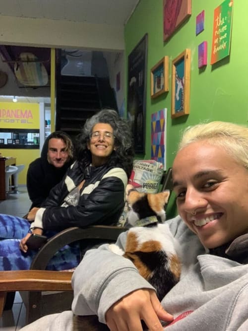Hóspedes sorrindo na Hostel New Ipanema no Rio de Janeiro, segurando um cachorrinho em uma sala comum vibrante
