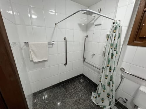 Banheiro moderno no Pouso do Barão em Domingos Martins, com azulejos brancos, piso de granito escuro e estampa de cacto
