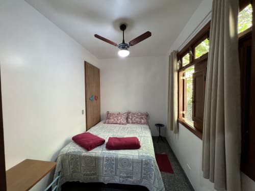 Quarto luminoso na Pousada do Barão com cama de casal, ventilador de teto e vista para o jardim