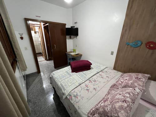 Quarto aconchegante no Pouso do Barão com duas camas, almofada bordô, TV e vista para o jardim em Domingos Martins