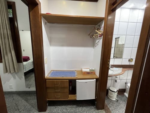Quarto compacto no Pouso do Barão em Domingos Martins com cama de madeira, frigobar e acesso ao banheiro