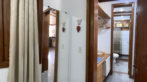 Corredor da Pousada do Barão em Domingos Martins com molduras de madeira, enfeites decorativos em forma de coração e entrada do banheiro