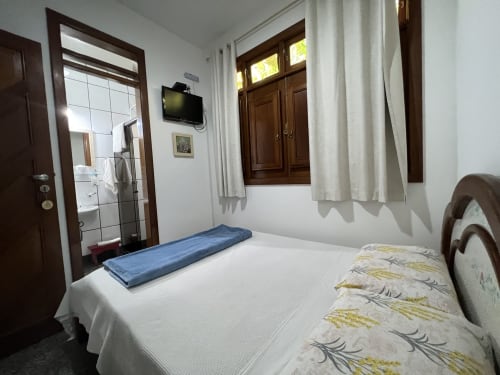 Quarto no hotel Pouso do Barão em Domingos Martins com camas individuais, banheiro privativo e vista para o jardim