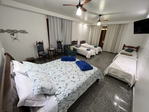 Espaçoso quarto com várias camas no hotel Pouso do Barão em Domingos Martins, com vista para as montanhas, ventiladores de teto e comodidades modernas.
