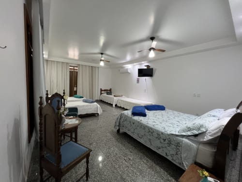 Espaçoso quarto com múltiplas camas no Pouso do Barão com vista para as montanhas, ventiladores de teto e comodidades modernas em Domingos Martins