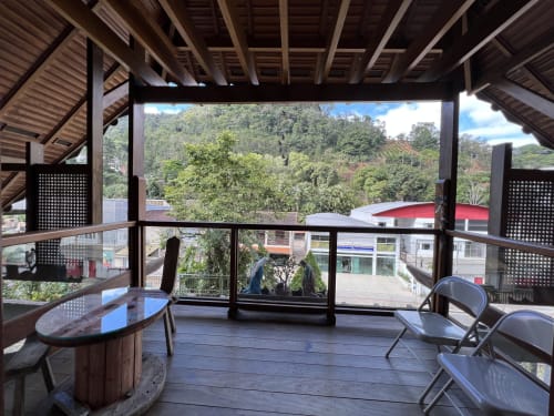 Vista da montanha da ampla varanda do hotel Pouso do Barão em Domingos Martins, Brasil, com móveis modernos e floresta