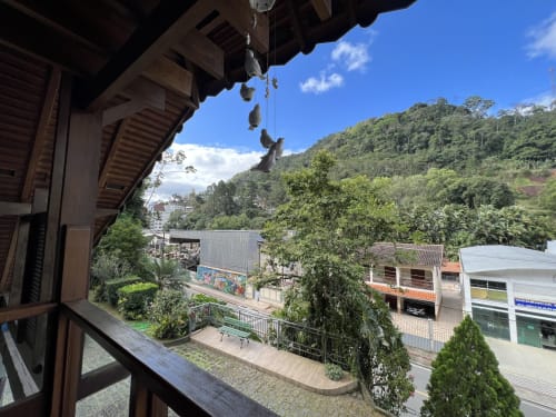 Vista da serra do Pouso do Barão da varanda do quarto com colinas verdes exuberantes e construções locais em Domingos Martins