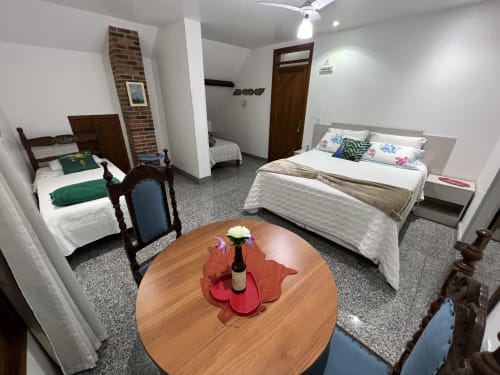 Aconchegante quarto de hotel no Pouso do Barão com duas camas de solteiro, móveis de madeira e mesa redonda em Domingos Martins