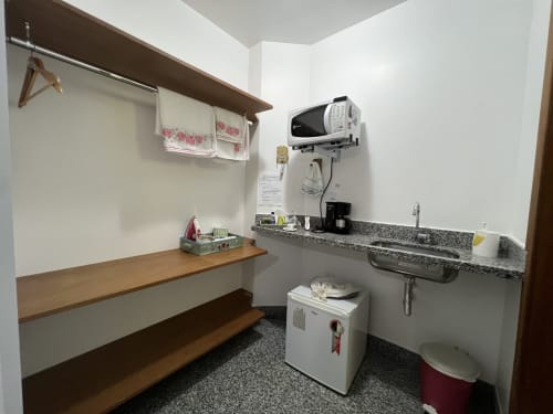 Pequena kitchenette do hotel Pouso do Barão em Domingos Martins com micro-ondas, pia e bancada