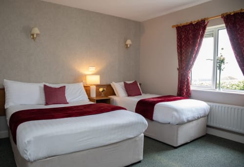 Twin beds with burgundy runners in bright hotel room with garden view at Sliabh Beagh Hotel, Monaghan